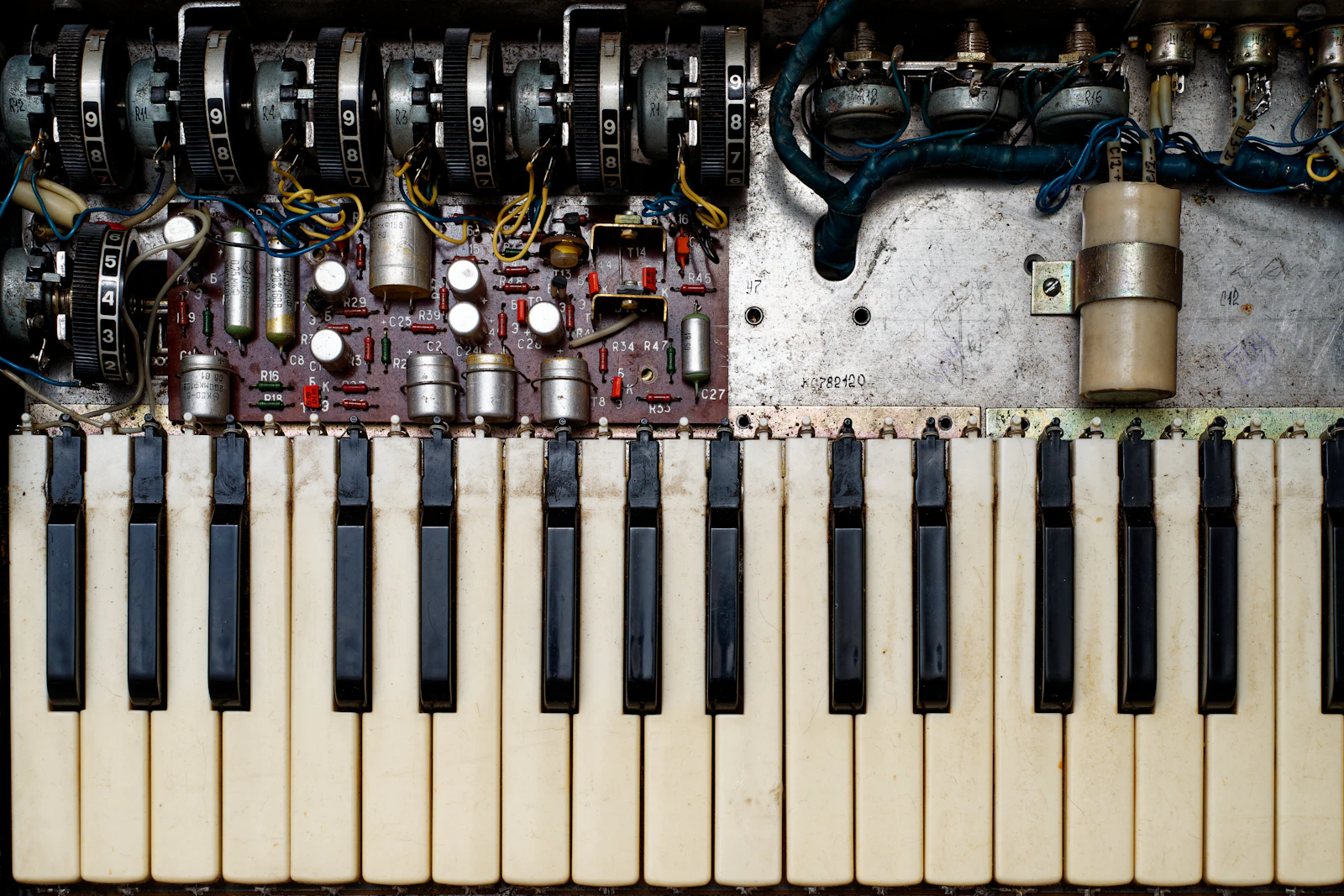 Vintage synthesizer with all panels open, internal modules visible, diagnostic tools arranged nearby