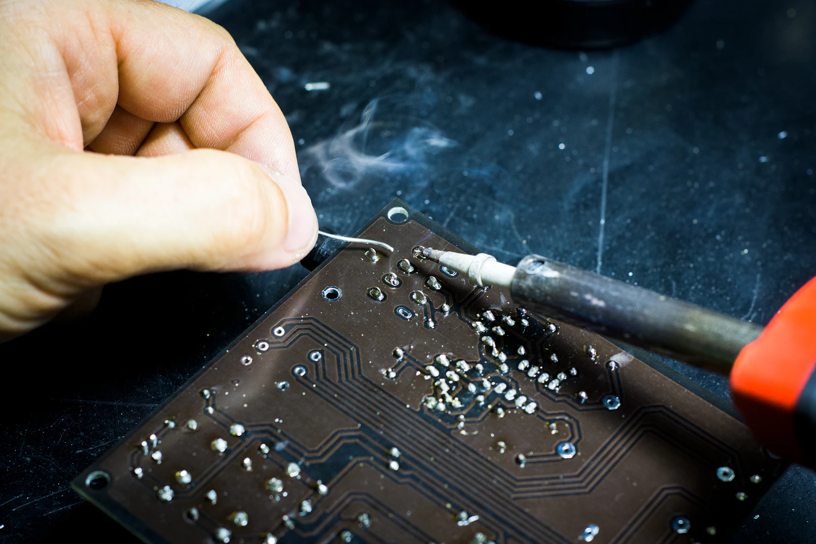 Soldering iron mid-work on a circuit board, capacitor being replaced on a 1970s synthesizer